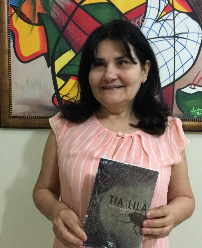 Imagem de Joana Belarmino segurando seu livro Tia Lila, publicado no ano de 2018