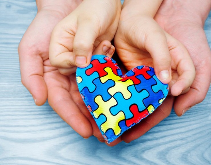 Imagem de duas mãos de adulto e duas mãos de criança segurando um coração formado por peças de quebra-cabeça, com azul como cor predominante 
