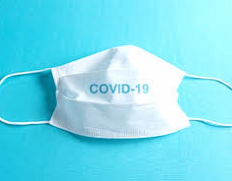 Imagem de uma máscara sobre uma superfície, com a palavra Covid-19 escrita